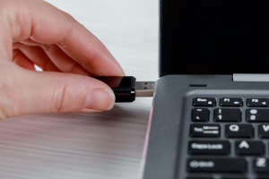 Female hand insert a USB memory stick into the side of a laptop